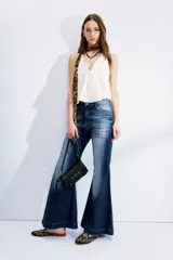 Pantalón de jean de tiro medio, color azul con desgaste y bigotes. De corte ajustado en cintura y cadera, con pierna acampanada.