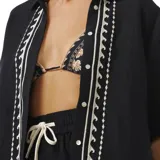 Camisa negra de manga corta con bordado de conchas marinas y motivos geométricos en blanco.