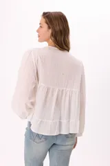 Blusa blanca de mangas largas abullonadas, con escote en V con lazo y volados.