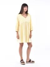 Vestido corto color amarillo pálido, con escote en V, mangas 3/4 y detalle de bordado calado en el canesú.