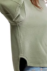 Camiseta de manga larga color verde oliva, con textura acanalada y silueta holgada extragrande. Presenta escote redondo, hombros caídos y puños anchos.