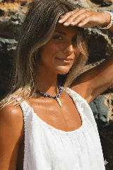 Collar corto con cuentas de cuarzo azul y dije de colmillo de nácar con dije de acero.