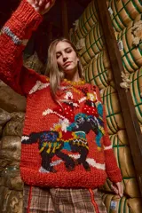 Sweater tejido a mano con lana color ladrillo, cuello redondo, puños y ruedo acanalados con rayas blancas. Presenta bordados con figuras de personas y animales.