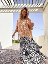 Vestido camisero largo con estampado de hojas en tonos marrones y blancos en la parte superior, y estampado de cebra en blanco y negro en la parte inferior.
