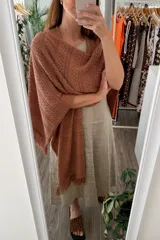 Ruana tejida color marrón terracota, con diseño calado de puntos y terminaciones con flecos.