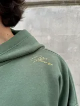 Hoodie verde militar de felpa con frisa gruesa, corte boxy y estampado en la espalda con la frase "BURN THE SHIPS. To fully commit to a course of action, with no possibility of retreat.".