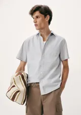 Camisa celeste con estampado de microcuadros, de manga corta, con cuello clásico y bolsillo en el pecho.