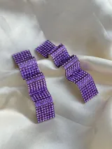 Par de aros colgantes con forma geométrica irregular, cubiertos de strass color lila.