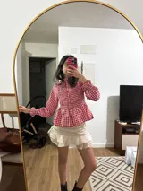 Camisa roja con estampado de cuadros blancos, cuello mao, mangas largas abullonadas con puños elásticos y peplum.