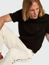 Remera de algodón color blanco roto con cuello redondo y un pequeño logo de estrella negra estampada en el pecho.