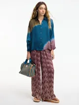 Camisa de manga larga con estampado tie-dye en tonos marrón, azul y lila. Tiene cuello camisero, cierre frontal con botones y corte amplio.