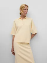 Polo de punto doble color amarillo, con cuello tipo polo y cierre de cuatro botones, de manga corta.