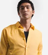 Camisa celeste de lino con cuello camisero, abotonadura frontal y mangas largas.