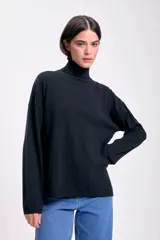 Polera negra de punto de rib con cuello alto y mangas largas.
