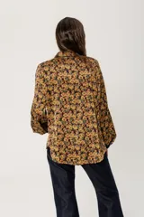 Camisa de seda con estampado de flores tipo hippie en colores mostaza, verdes y ocre con botones símil metal y cuello clásico.