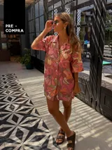 Camisa oversize de manga corta con cuello solapa y botones frontales. Presenta un estampado floral grande en tonos rosados, naranjas y verdes.