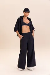 Pantalón negro de corte palazzo, con cintura elástica y bolsillos laterales.