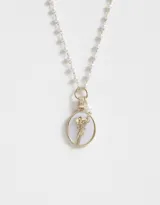 Collar corto con cadena de perlas blancas y dije ovalado con borde dorado y flor dorada en el centro.