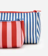 Kit de tres neceseres de diferentes tamaños. Incluye un neceser grande transparente con bordes y asa de mano en color azul, y dos neceseres internos más pequeños con estampado de rayas verticales en azul y blanco. Todos cuentan con cierre de cremallera.