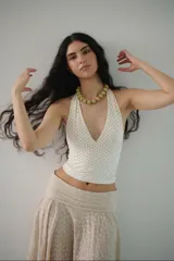 Top blanco con lunares negros, escote en V y tiras para atar detrás del cuello.