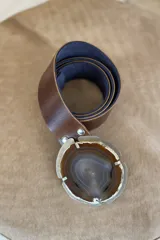 Cinto de cuero azul con hebilla circular de piedra ágata con borde dorado.