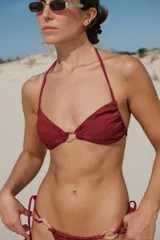 Top de bikini negro con textura, corte triangular, breteles finos y argolla decorativa de resina en el centro.