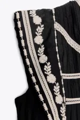 Minivestido negro de algodón con bordados florales blancos en cuello, mangas y ruedo.