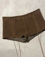 Shorts de gamuza color marrón oscuro, de tiro alto, con cordones cruzados a los costados a modo de ajuste o decoración.