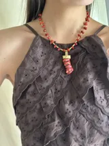 Collar corto con cuentas de coral rojo y detalles de bronce. Incluye un dije con forma de cuerno de la abundancia.