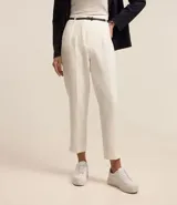 Pantalón de vestir rojo, estilo carrot (holgado en cadera y ajustado en tobillo), con pliegues frontales y cinturón de material sintético negro con hebilla pequeña.