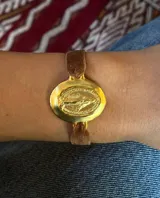 Pulsera elástica de terciopelo marrón con medalla ovalada dorada de la Virgen María.