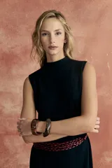 Vestido midi negro sin mangas, de tejido de punto con cuello alto y corte recto. Incluye cinturón fino marrón trenzado y botas de cuero marrón oscuro.