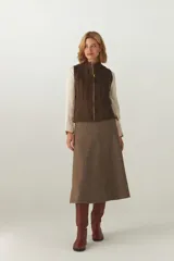 Chaleco color crema con cuello alto y cierre frontal con cremallera. Diseño con alforzas verticales en la parte superior delantera y trasera.