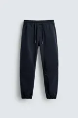 Pantalón jogger negro de corte slim fit, confeccionado en tejido de algodón con cintura elástica ajustable con cordón, bolsillos frontales y traseros de vivo, y bajo con puño elástico.