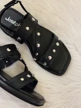 Sandalias negras de cuero sintético con tiras cruzadas y apliques de tachas plateadas.