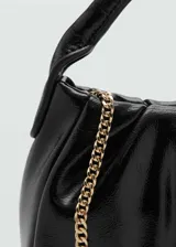 Bolso de mano negro con diseño acolchado, forro interior y doble asa corta.