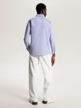 Camisa celeste de corte regular Tommy Hilfiger, confeccionada en algodón Oxford con microestampado de puntos azules. Tiene cuello abotonado, manga larga y logo bordado en el pecho.