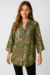 Camisa verde militar con estampado floral, corte holgado, cuello en V, cierre frontal con botones y mangas 3/4. Presenta dos bolsillos de simil cuero en el pecho.