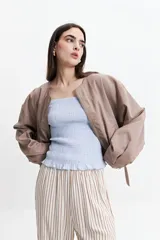 Campera corta color verde militar, sin cuello, con cierre frontal y elástico en la cintura. Tiene bolsillos amplios y mangas largas con puños elásticos.