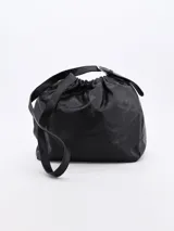 Morral negro de cuero sintético con fruncido superior y correa larga regulable.