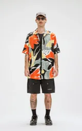 Camisa de manga corta con estampado abstracto en tonos naranja, negro, gris y amarillo. Tiene calce oversize y canesú en la espalda.