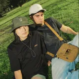 Sombrero negro tipo pescador, confeccionado en poliéster reciclado. Tiene ala mediana, ajuste elástico en la corona y tira ajustable con tanca.