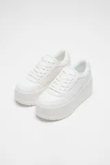 Zapatillas blancas con plataforma gruesa, cordones y puntera redonda.