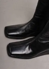 Bota de cuero negra, de caña media, punta cuadrada y taco bajo forrado.