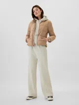 Campera puffer color crema, con manga larga, cuello alto y cremallera frontal, fabricada con relleno 100% reciclado.