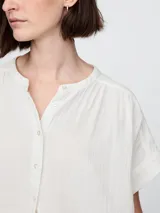 Camisa de muselina color blanco, con cuello mao y mangas cortas.