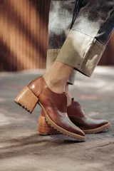 Zapatos de cuero color marrón con puntera fina, detalle de textura en el empeine, diseño slip-on y suela dentada.