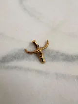 Dije plateado con forma de cráneo de toro con orificio en la frente.