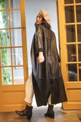 Tapado largo de cuero negro, de corte recto, sin botones ni bolsillos y cuello a la base.