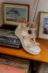 Sandalias de plataforma color beige con tiras decoradas con esferas doradas.